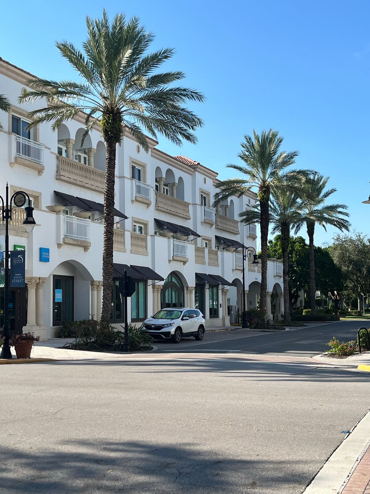 Palm trees and storefronts on a sunny street in Naples, Florida
