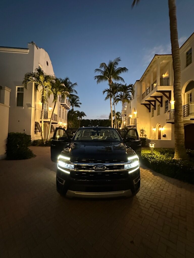 SP Prestige's black full-size SUV with headlights on outside a Naples residence at dusk